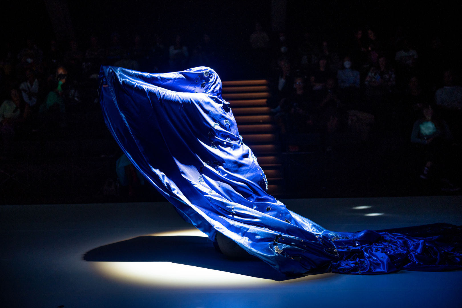 A body dances under a blue textile bedazzled with pieces of mirrored glass.